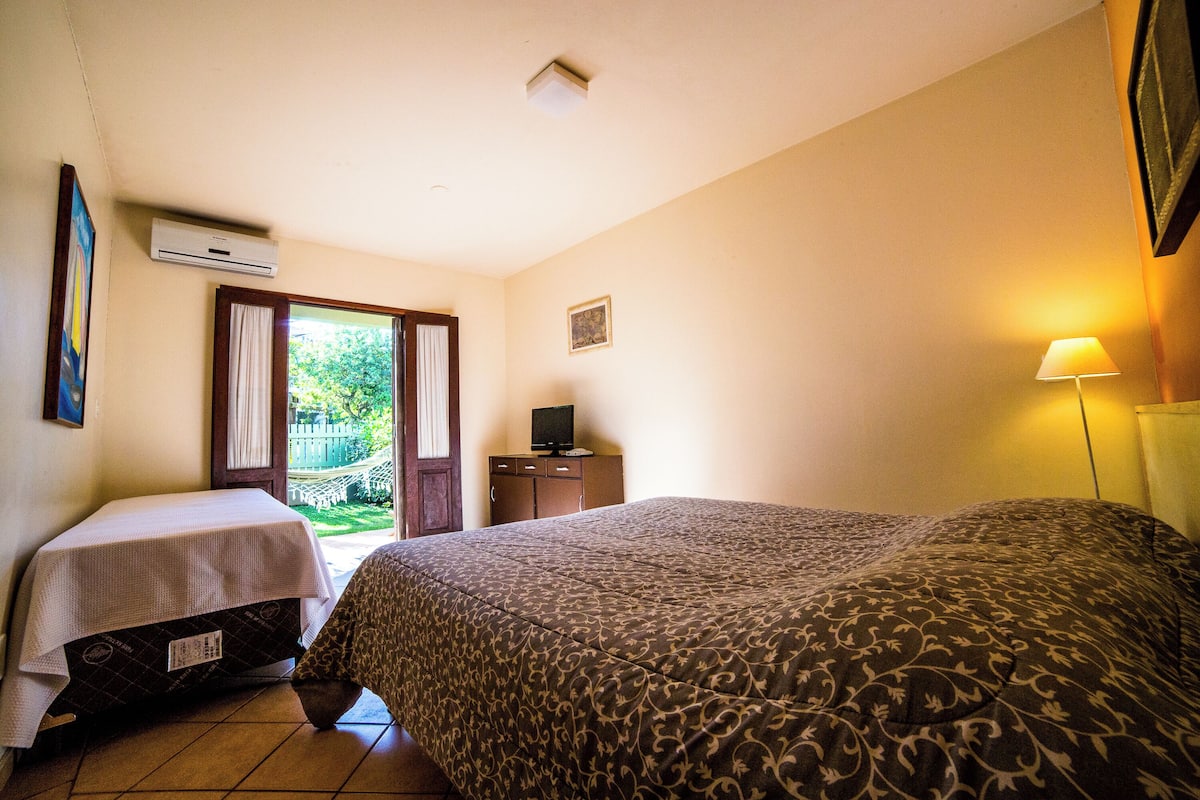Un dormitorio con una cama, una mesita, un televisor y una lámpara.