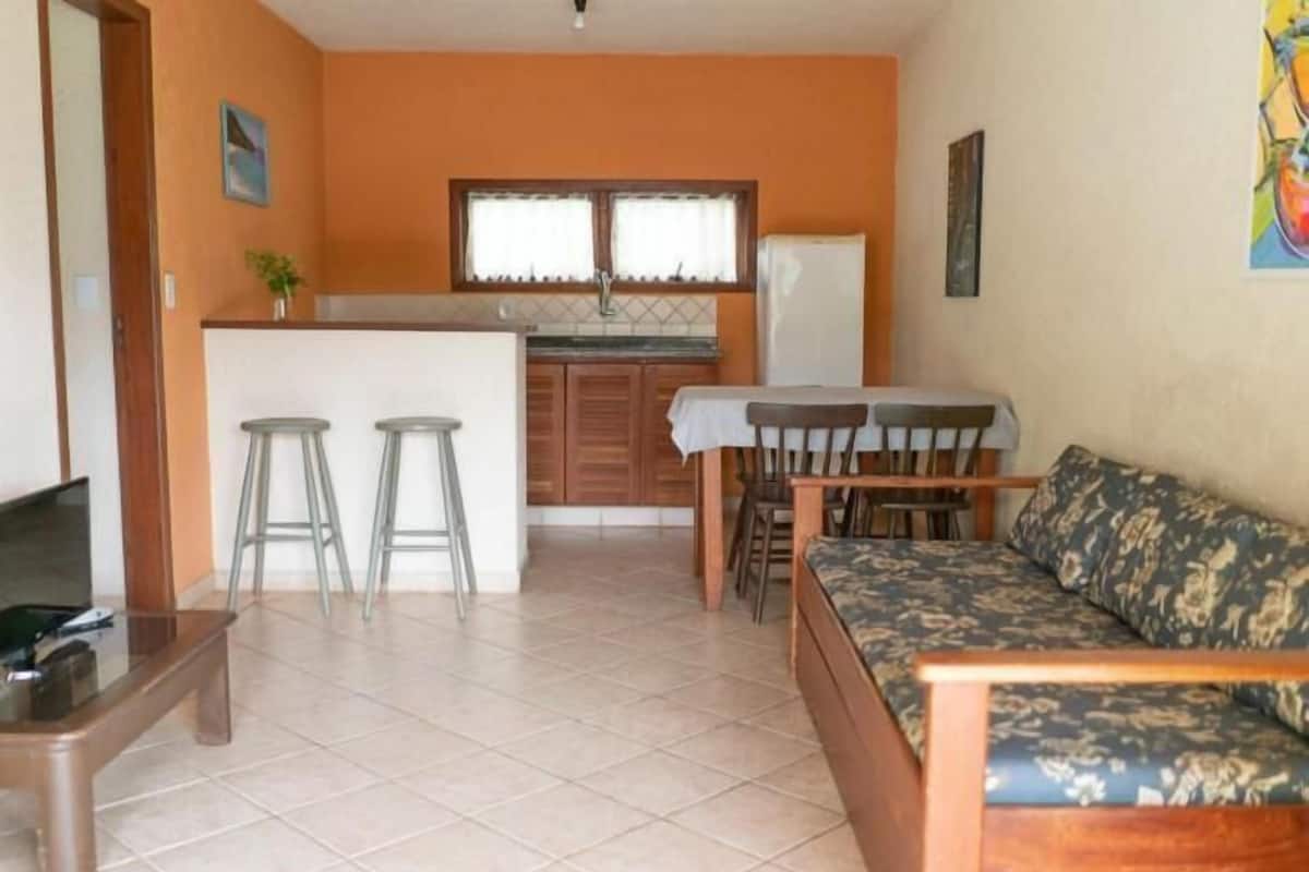 Un espacio habitable compacto con kitchenette, un sofá, una mesita de centro y un televisor.