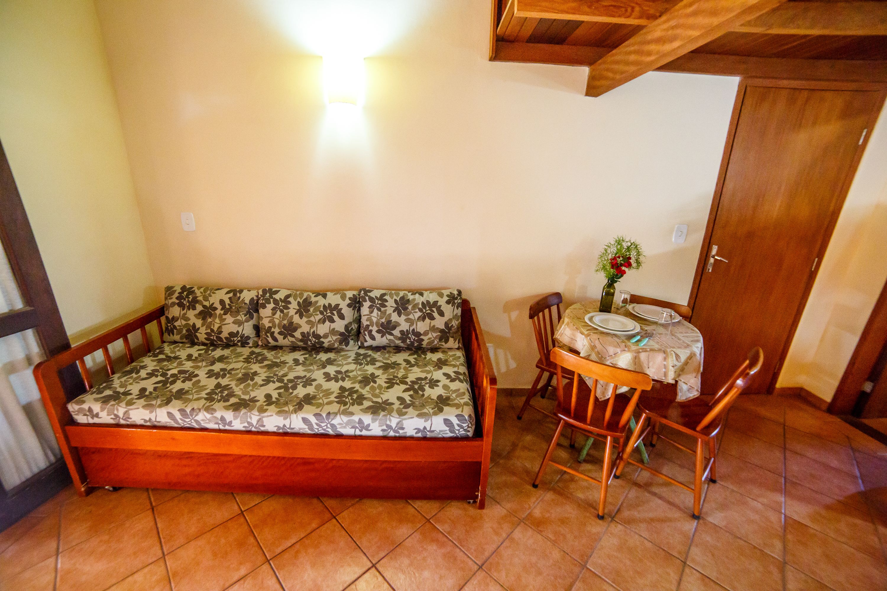 A room with a wooden sofa, a dining table with chairs, and a door.