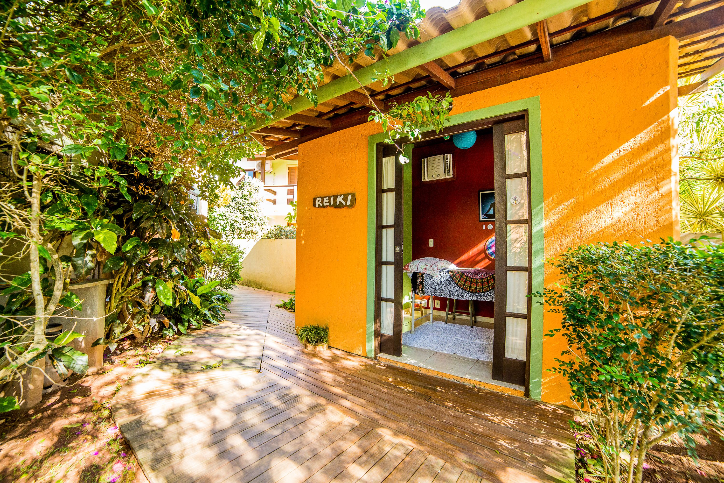 A wooden pathway leading to a building with an orange exterior and a green door.