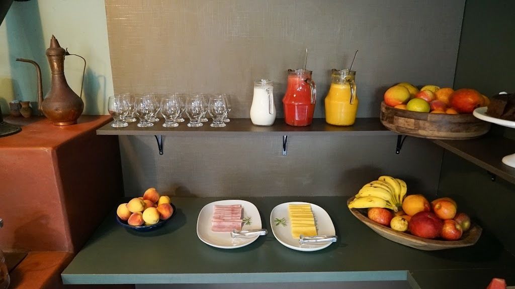 A breakfast buffet with various fruits, juices, and a selection of meats.