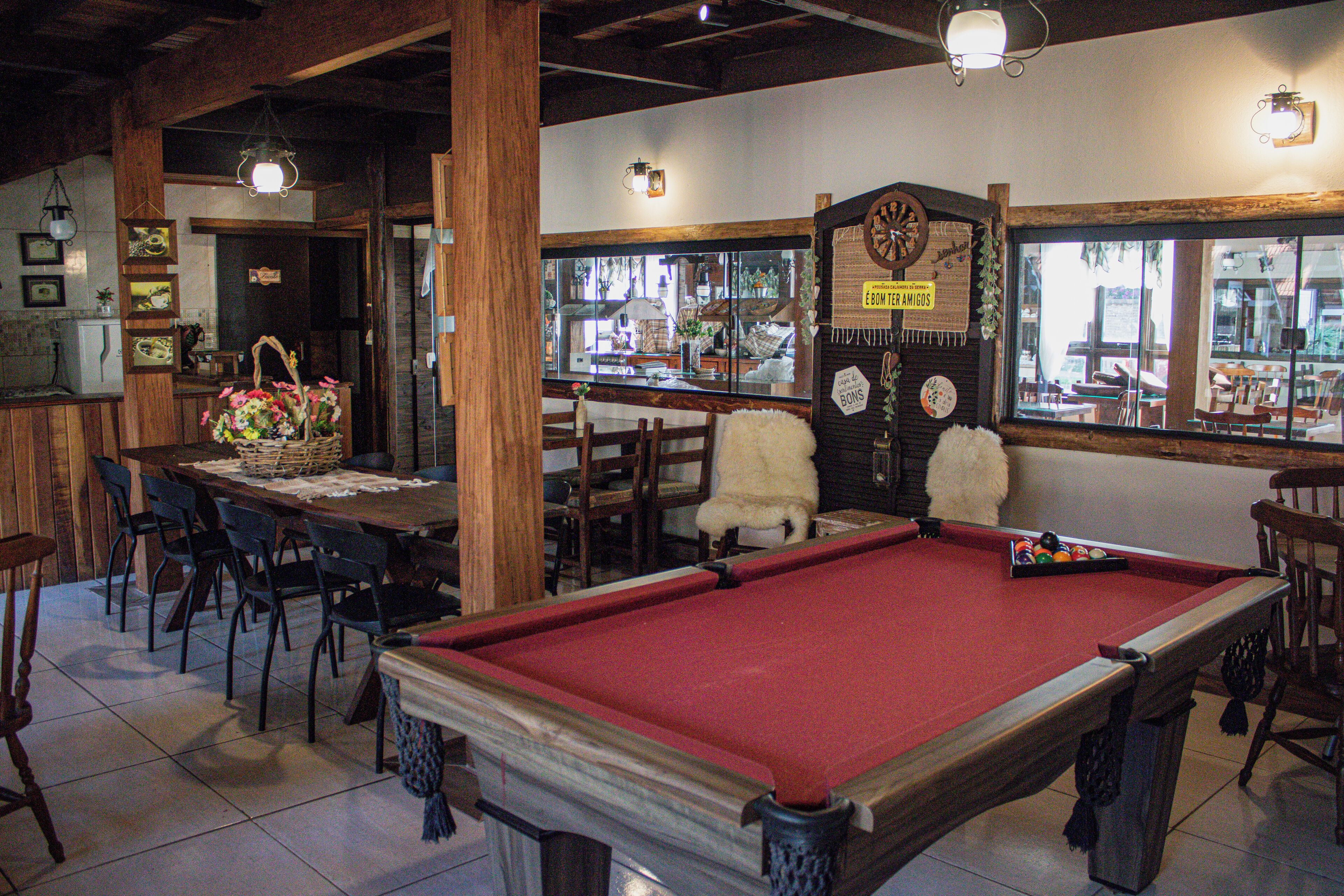 A billiards table in a room with wooden chairs, a dining table with chairs, and a window with a view of the outside.