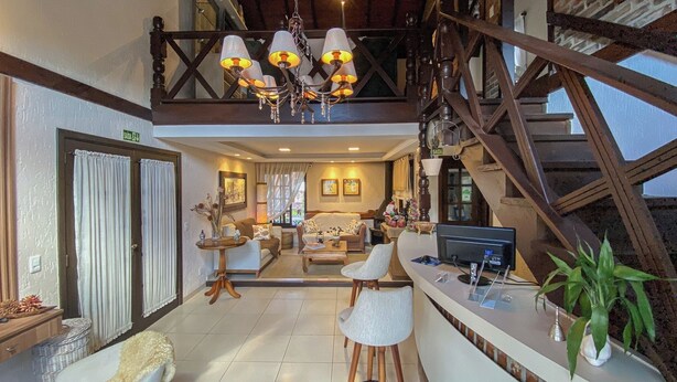 A spacious living area with a high ceiling, a staircase, and a dining area with a bar. - Pousada Caliandra da Serra (Canela)