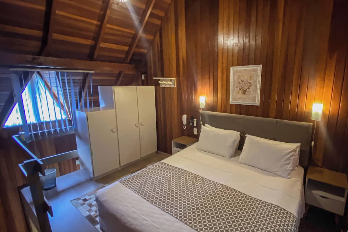 Ein Schlafzimmer mit einem großen Bett, Holzwänden, einem kleinen Nachttisch, einem Beistelltisch und einem Kleiderschrank.