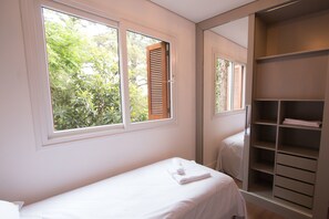 A bedroom with a single bed, a large mirror, and a wardrobe. - Residencial Florence (Gramado)