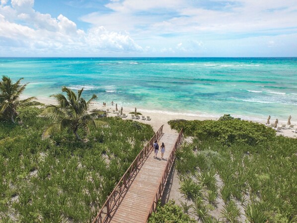 A wooden boardwalk leading to a beach with clear turquoise water and palm trees. - Unico Hotel Riviera Maya - Adults Only - All Inclusive (Kantenah)