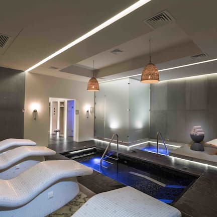A spa area with a pool, massage chairs, and a lounge chair.