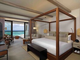 Un dormitorio amplio con una cama grande, un escritorio y vistas al océano.