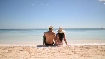 Una pareja sentada en una playa arenosa mirando al océano.