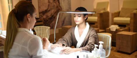 A salon with a massage chair, a reception desk, and a large mirror.