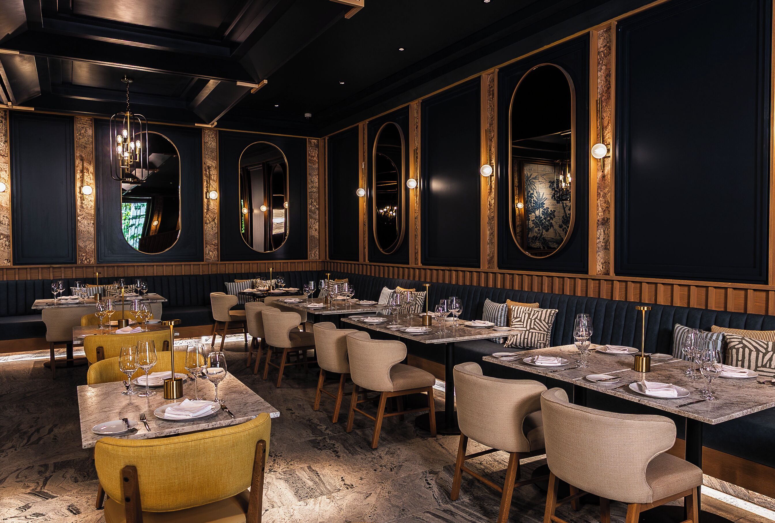 Un restaurante con varias mesas, sillas y un interior oscuro con detalles dorados.