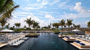 A pool area with lounge chairs and umbrellas, surrounded by palm trees and a clear sky. - Unico Hotel Riviera Maya - Adults Only - All Inclusive (Kantenah)