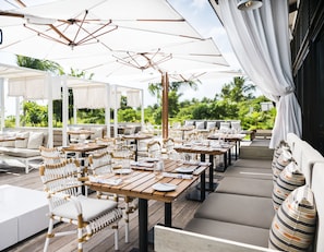 Enjoy al fresco dining under a shaded pergola surrounded by lush greenery.
