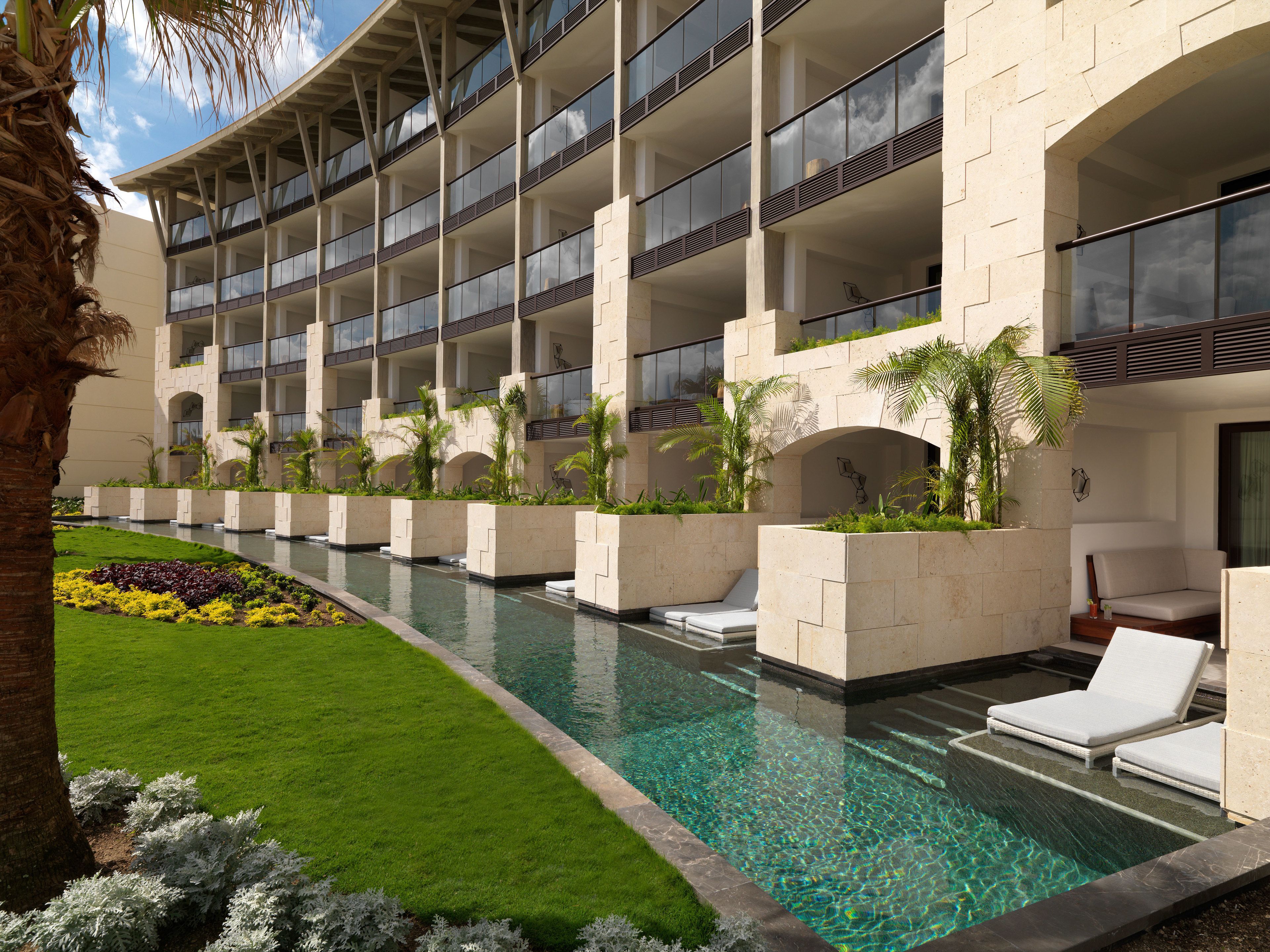 Hotel com várias varandas, piscina e paisagismo exuberante.