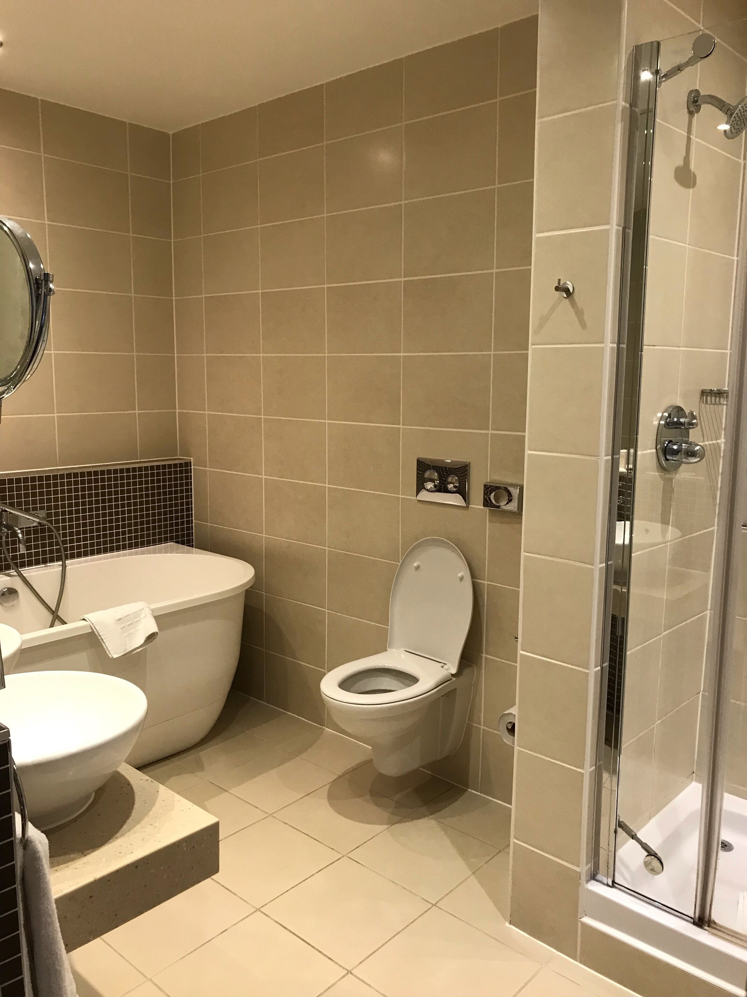 A modern bathroom with a bathtub, toilet, and glass-enclosed shower.