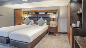 A modern hotel room with a large bed, bedside lamps, a small table, and a built-in wardrobe. - Felbridge Gatwick Hotel & Spa (East Grinstead)