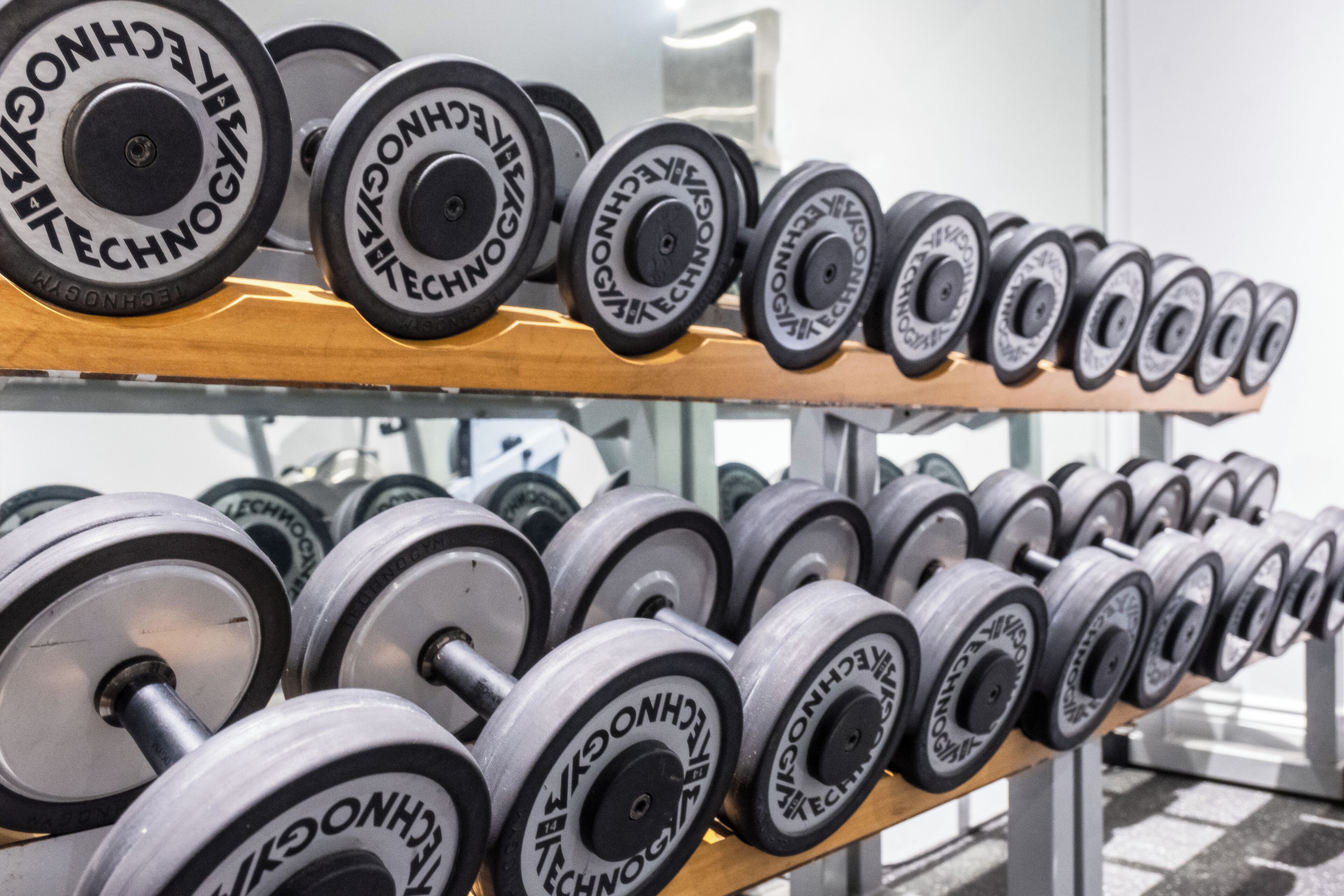 A rack of dumbbells with the brand name "TECHNOLOGY" visible on the weights.