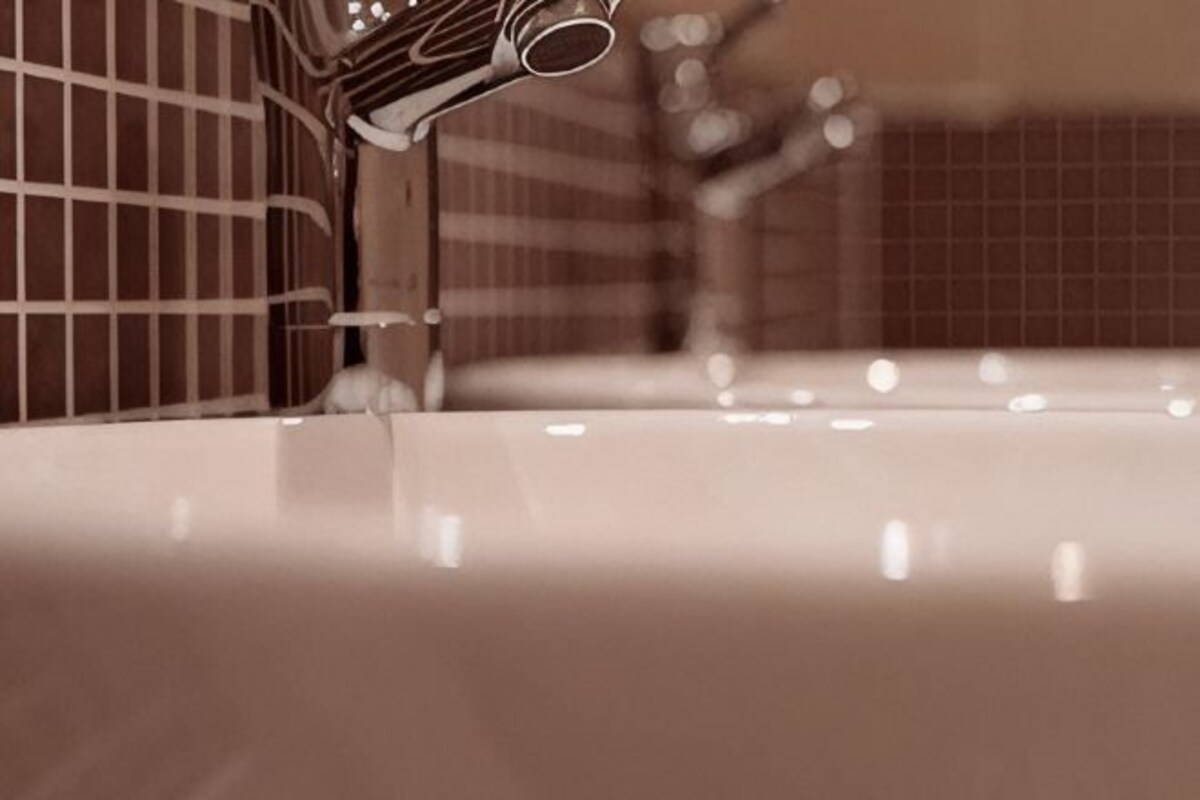 A bathroom sink with a faucet and a tiled wall.