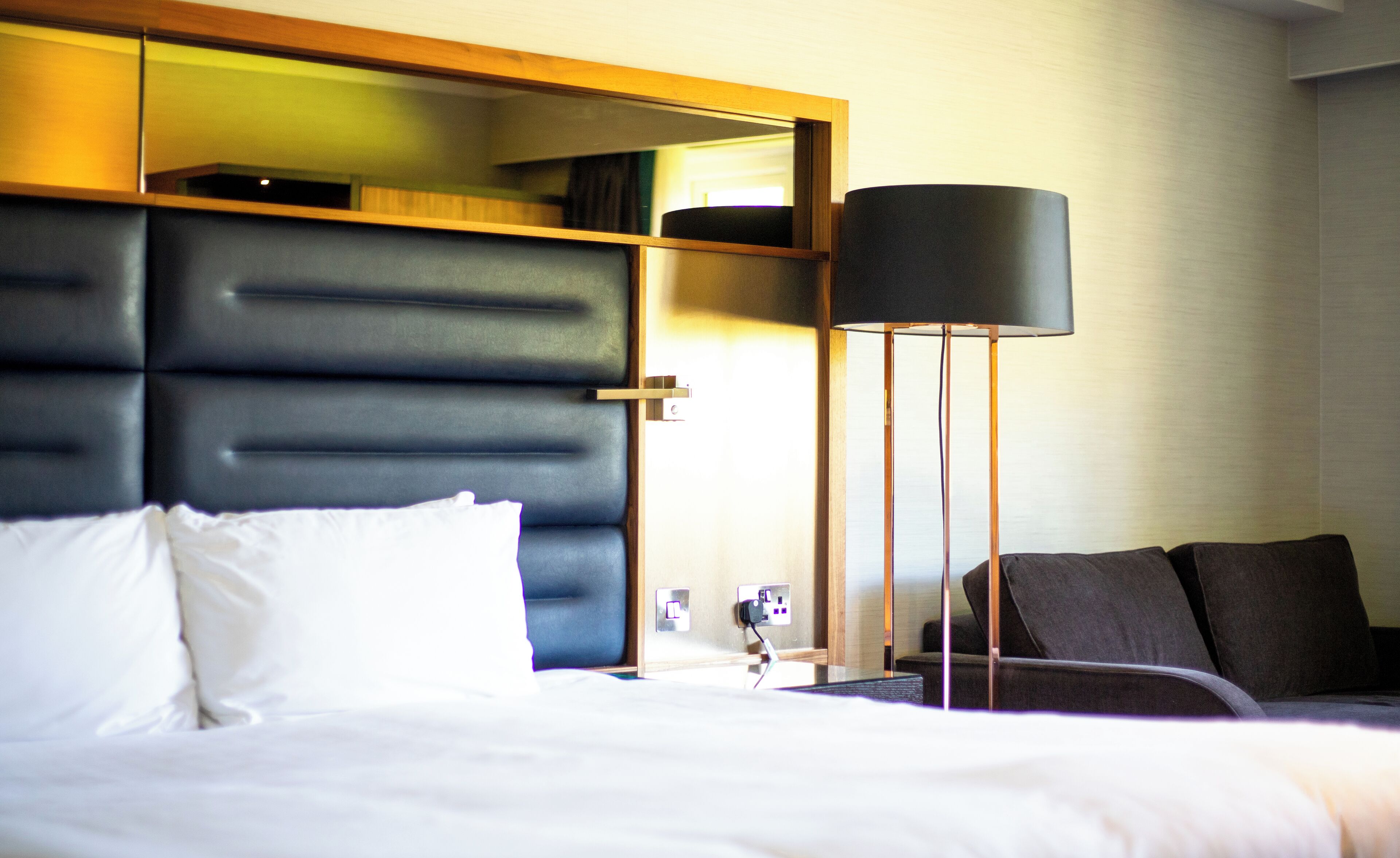 Een hotelkamer met een groot bed, een nachtkastje, een lamp en een kledingkast.