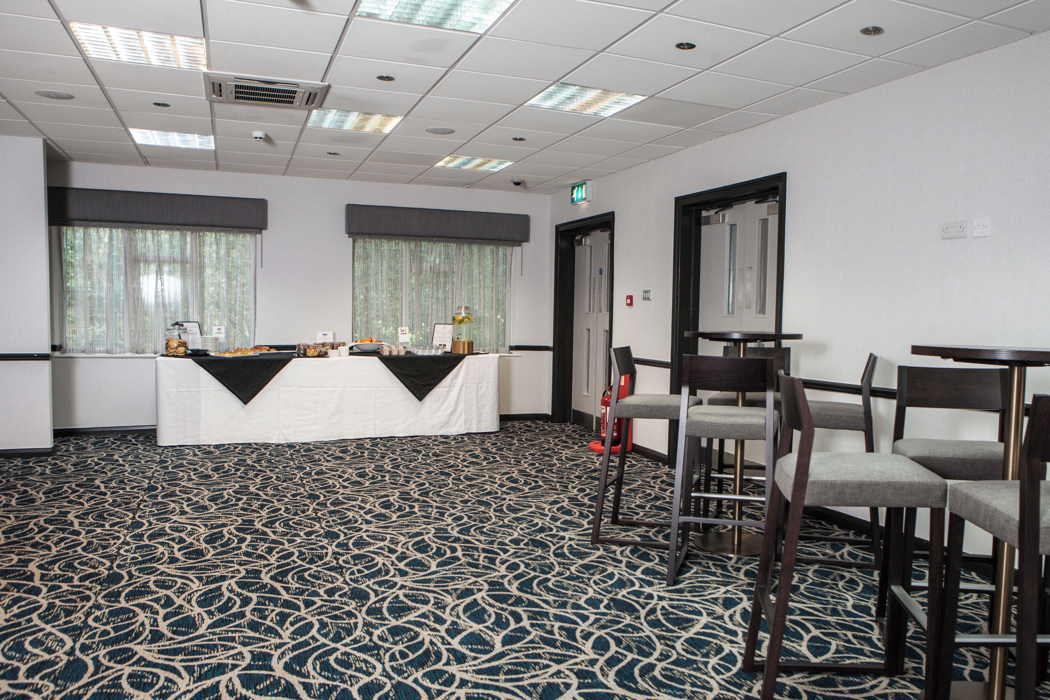 A conference room with a table, chairs, and a patterned carpet.