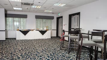 Un salón de conferencias con una mesa, sillas y una alfombra estampada.