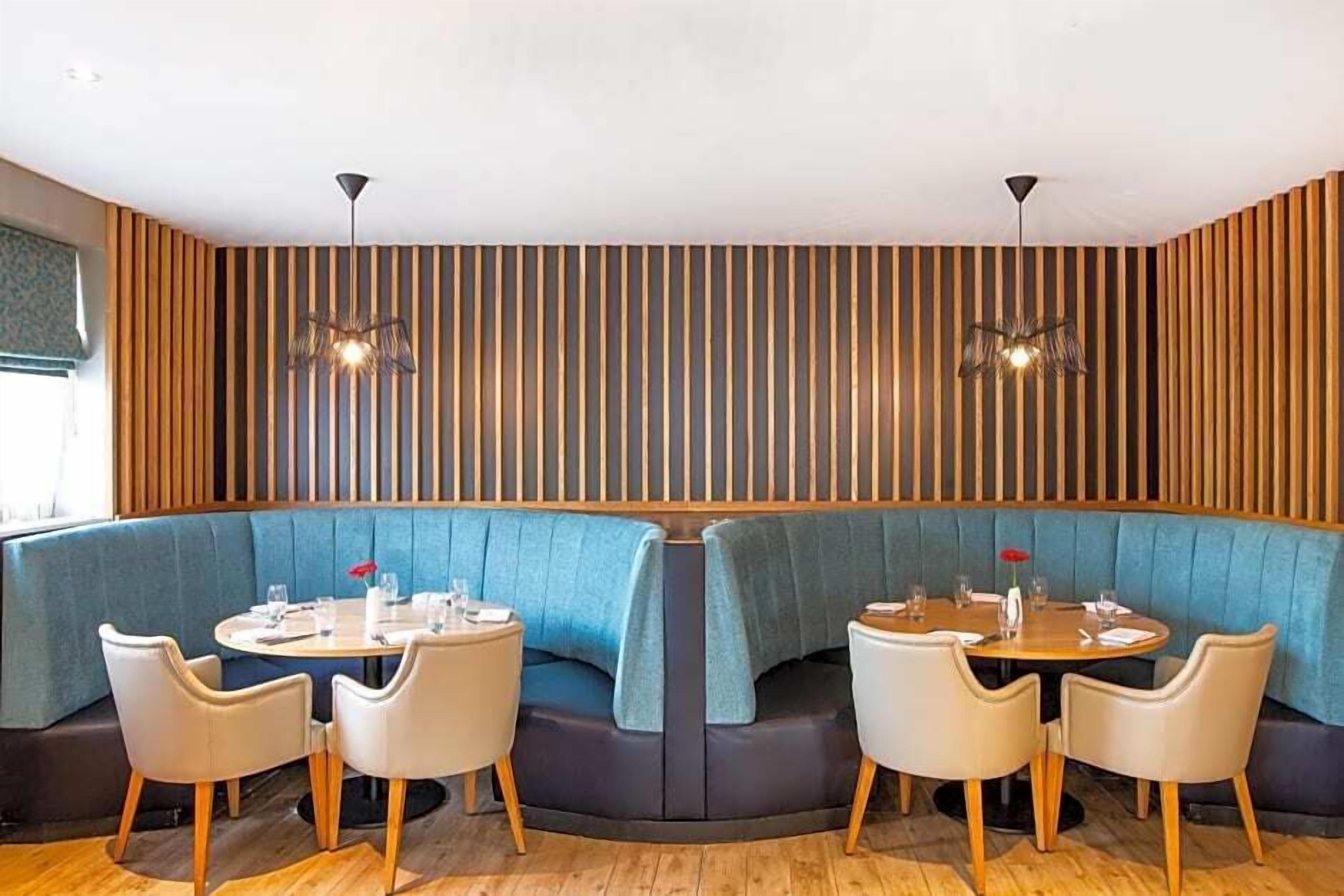 A restaurant with a curved seating area, wooden panel walls, and pendant lighting.