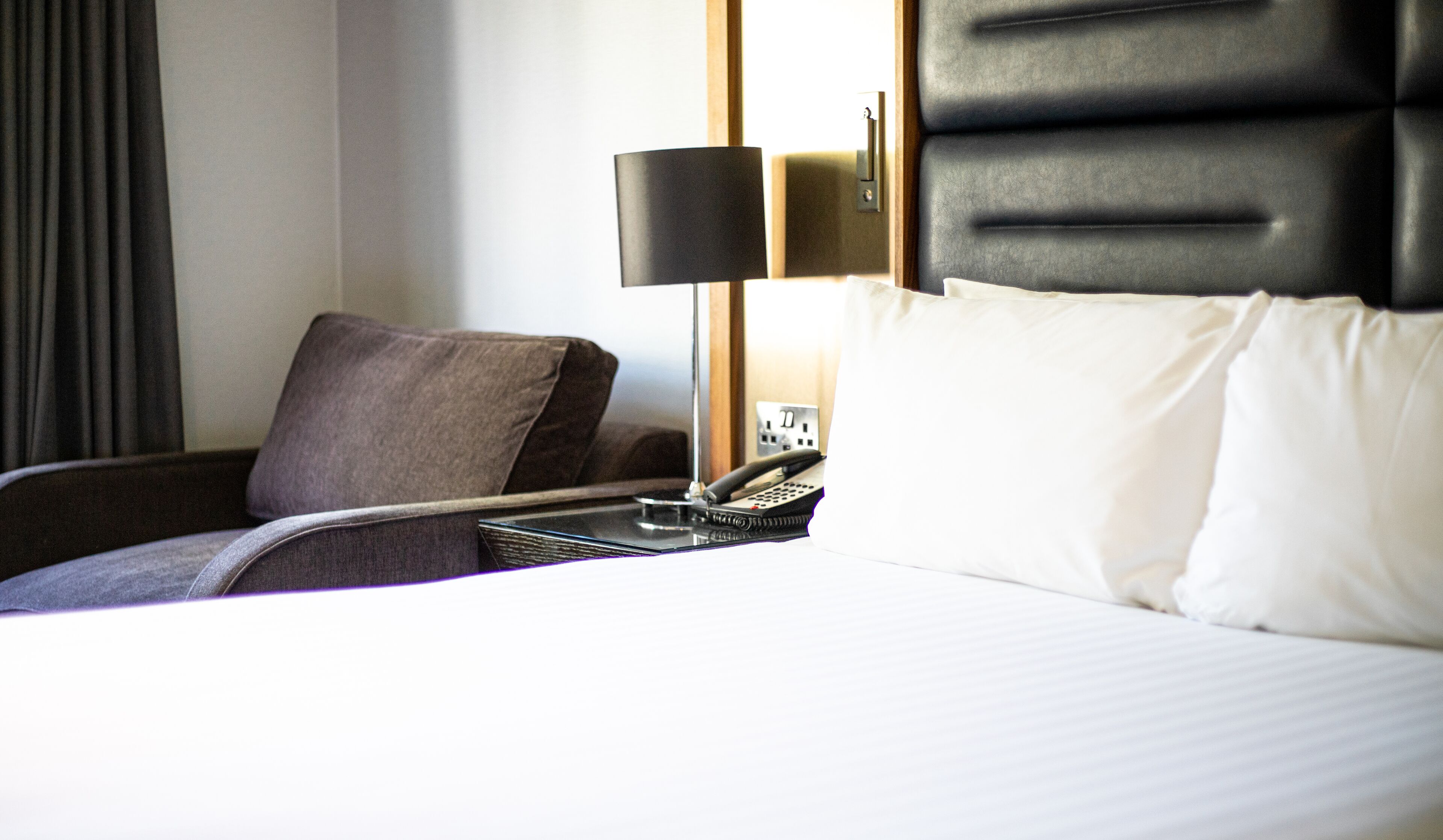 Una habitación de hotel con una cama, una silla, una lámpara y un teléfono.