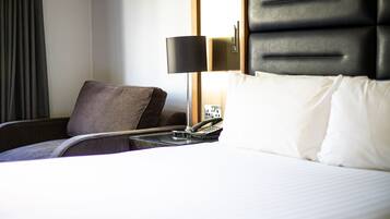Una habitación de hotel con una cama, una silla, una lámpara y un teléfono.