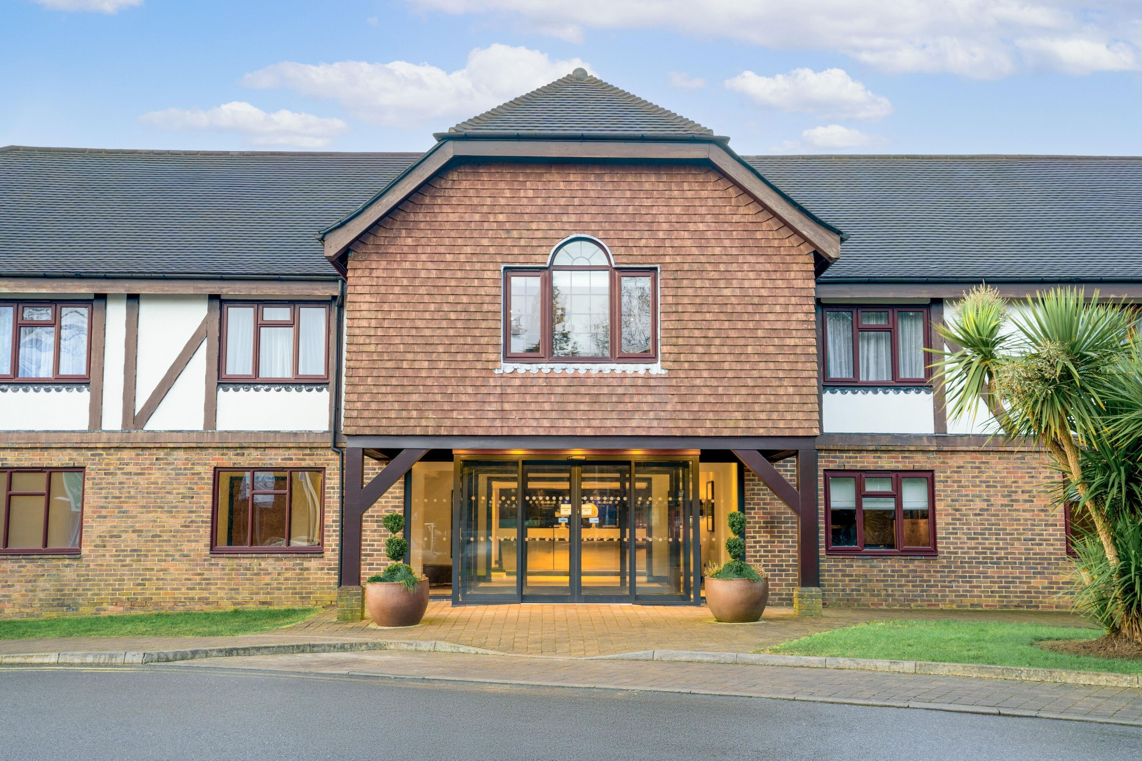 A two-story building with a symmetrical facade, large glass entrance doors, and a central arched window.