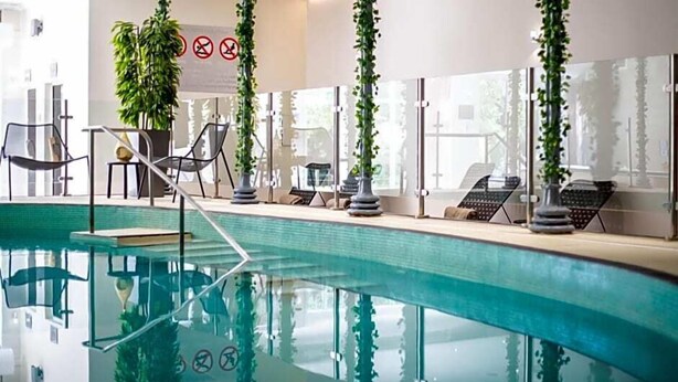 An indoor swimming pool with lounge chairs and a glass railing. - Felbridge Gatwick Hotel & Spa (East Grinstead)