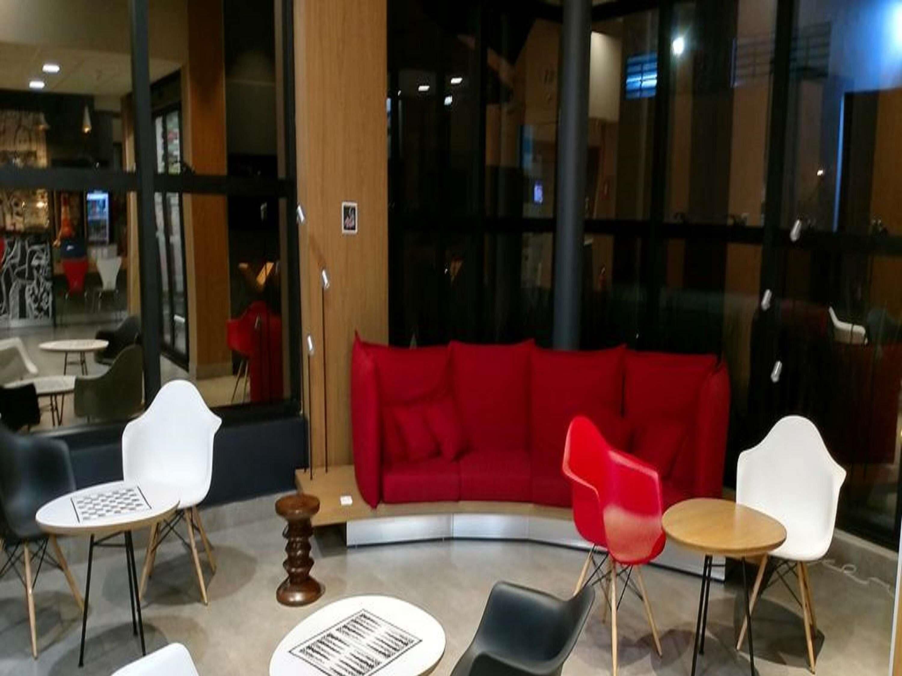 Un interior moderno con un sofá rojo, sillas blancas y rojas, y una pequeña mesa de madera.