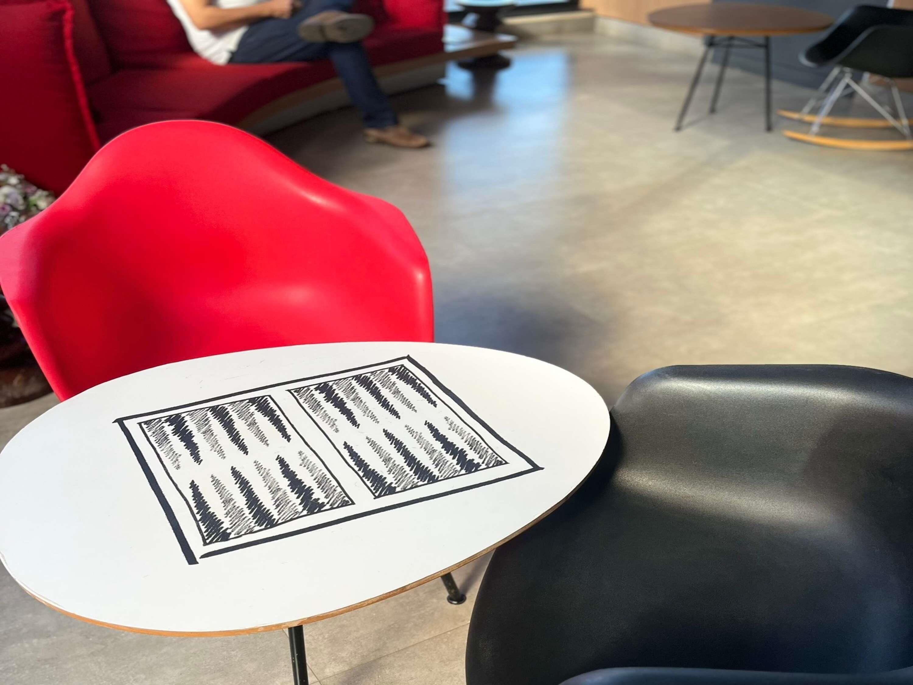 Una silla roja, una silla negra y una mesa blanca con un menú en un café.