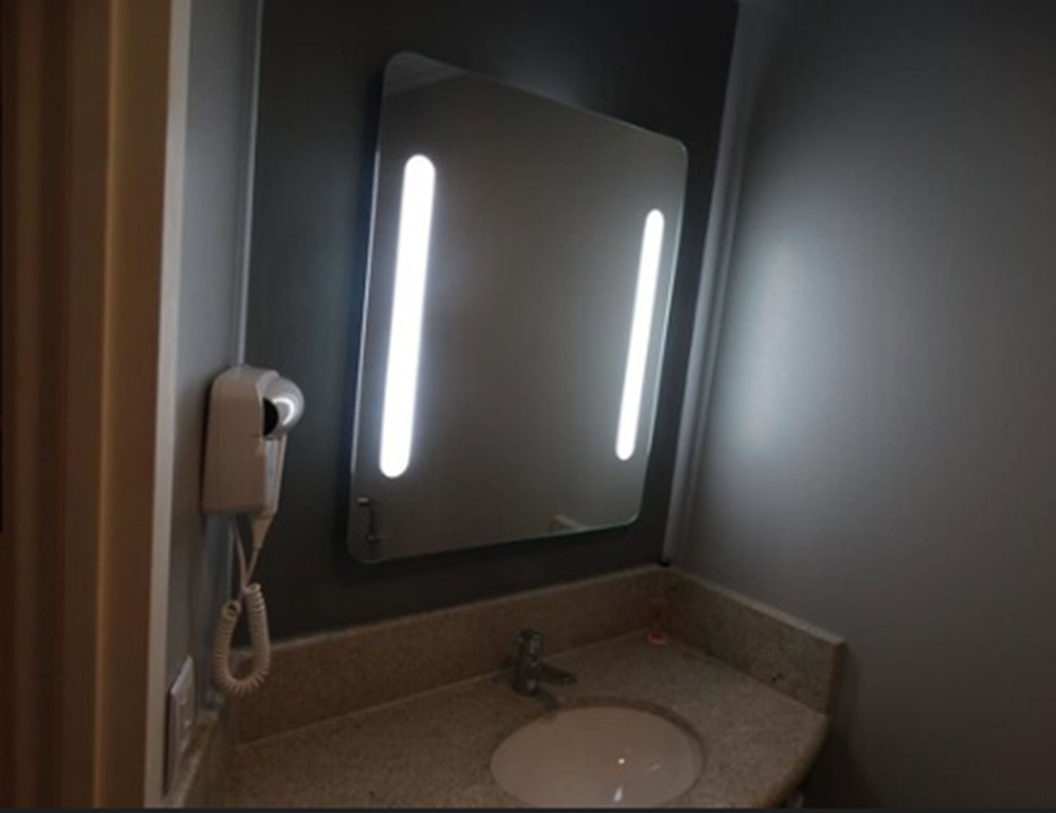 A bathroom with a sink, a mirror, and a telephone.
