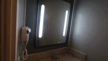 A bathroom with a sink, a mirror, and a telephone.