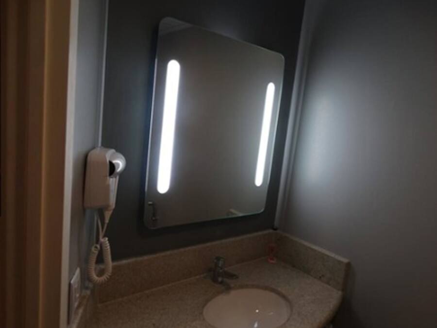 A bathroom with a sink, a mirror, and a telephone.