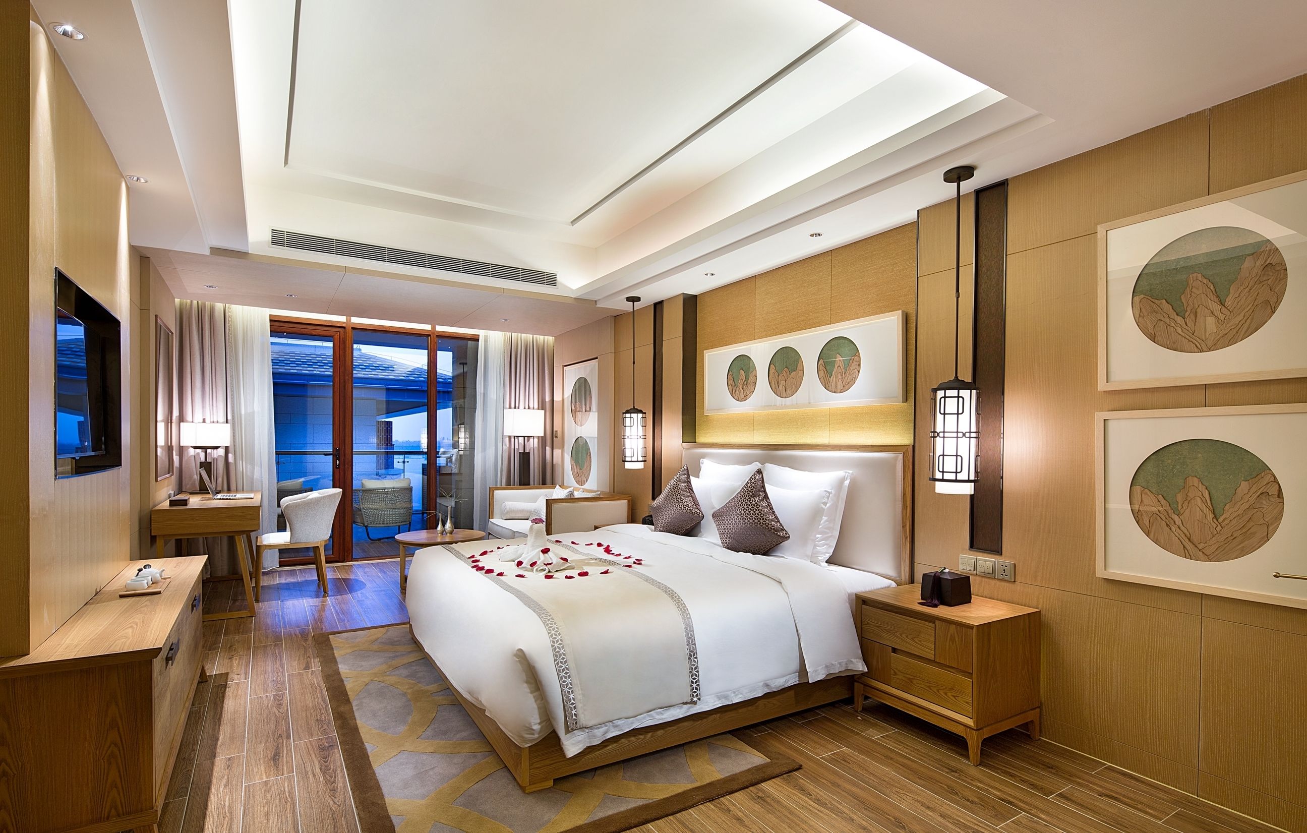 A modern hotel room with a large bed, a desk, a chair, and a view of the outdoors.