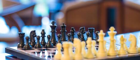 A chessboard with pieces in mid-game, set on a wooden table in a room with blurred background.