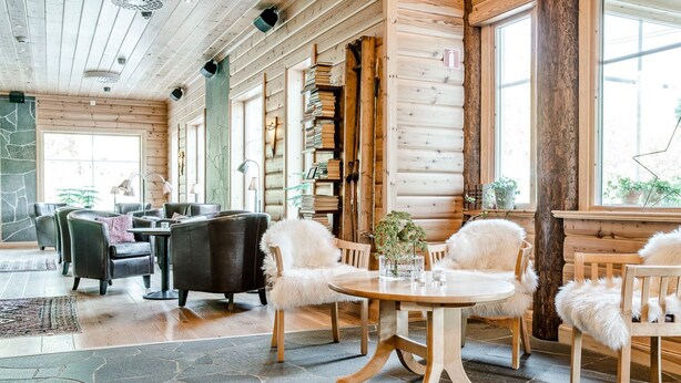 A cozy log cabin interior with a stone floor, wooden furniture, and large windows. - Storsätra Fjällhotell (Idre)