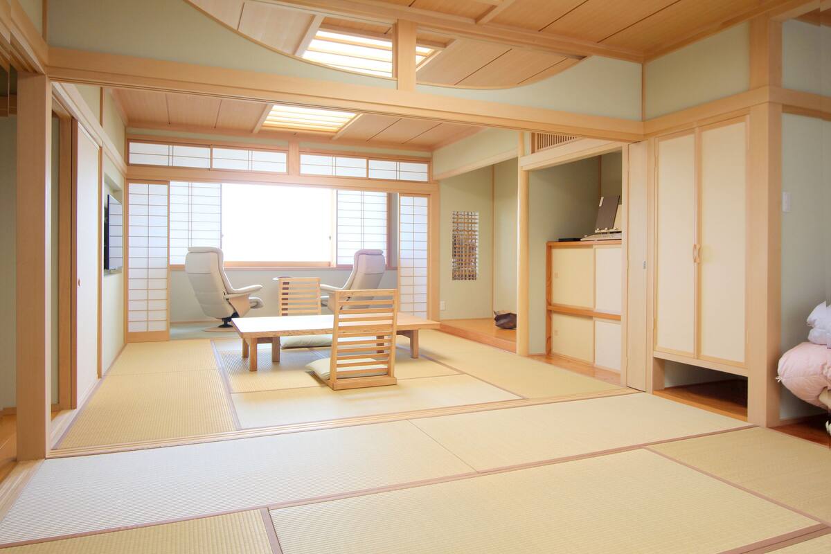 A traditional Japanese room with tatami flooring, a low table with cushions, and sliding doors.