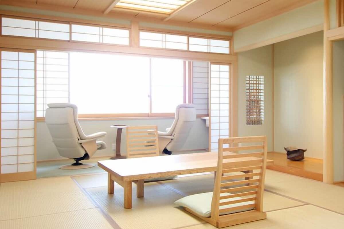 A traditional Japanese room with tatami flooring, a low wooden table, two chairs, and sliding shoji doors.