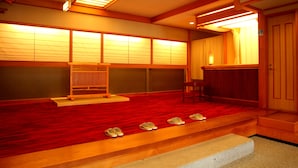 A traditional Japanese room with tatami flooring, a low wooden bench, and a sliding door.