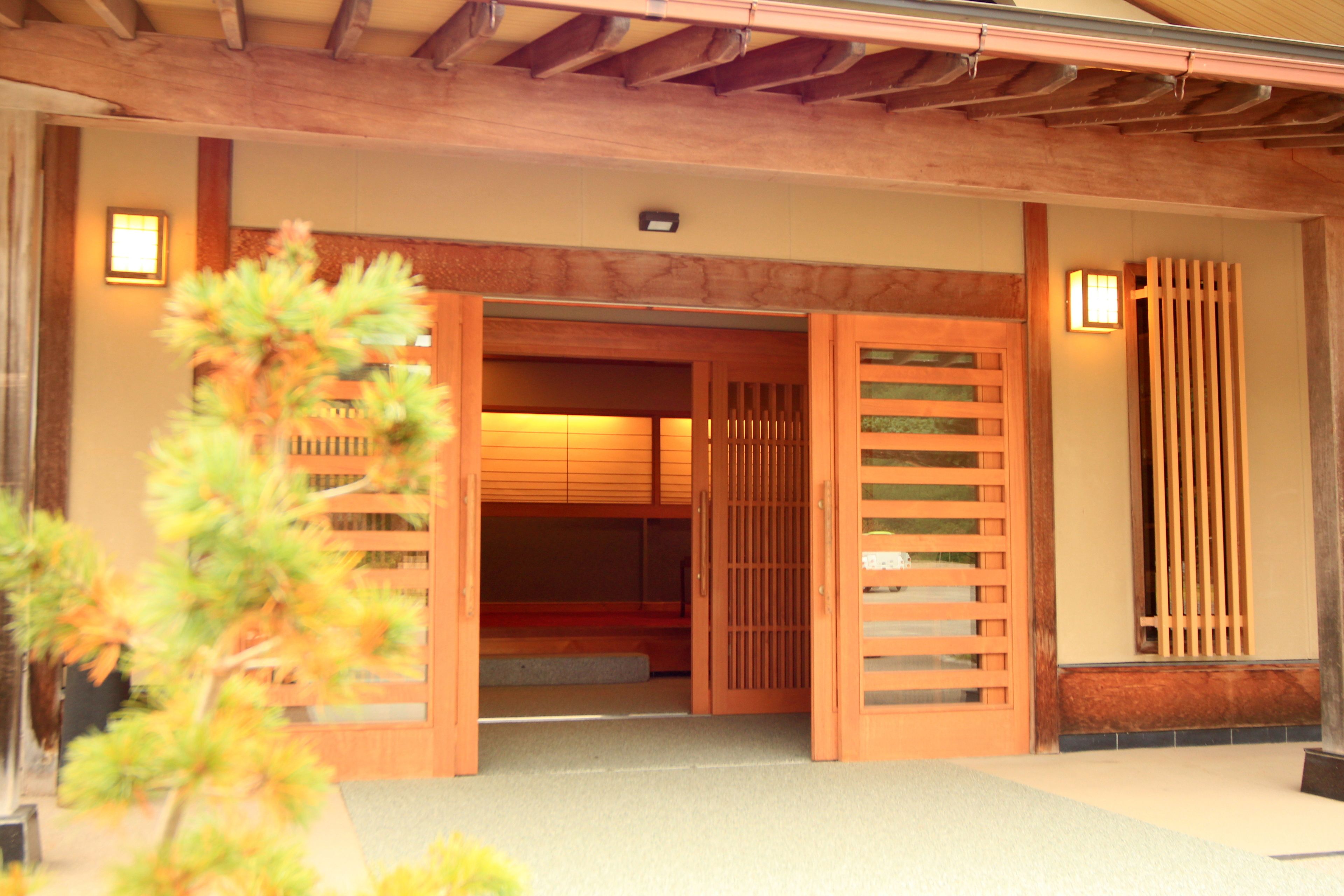 A traditional Japanese entrance with wooden sliding doors and a small garden area.