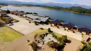 A lakeside hotel with a parking area, a swimming pool, and a view of the lake and mountains.