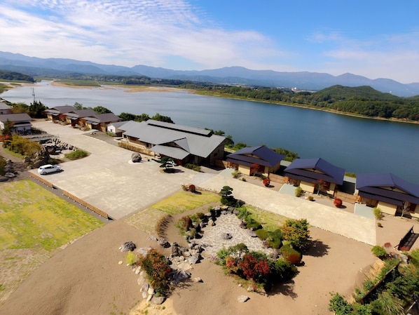 A lakeside hotel with a parking area, a swimming pool, and a view of the lake and mountains. - Bessou Kakei (Morioka)