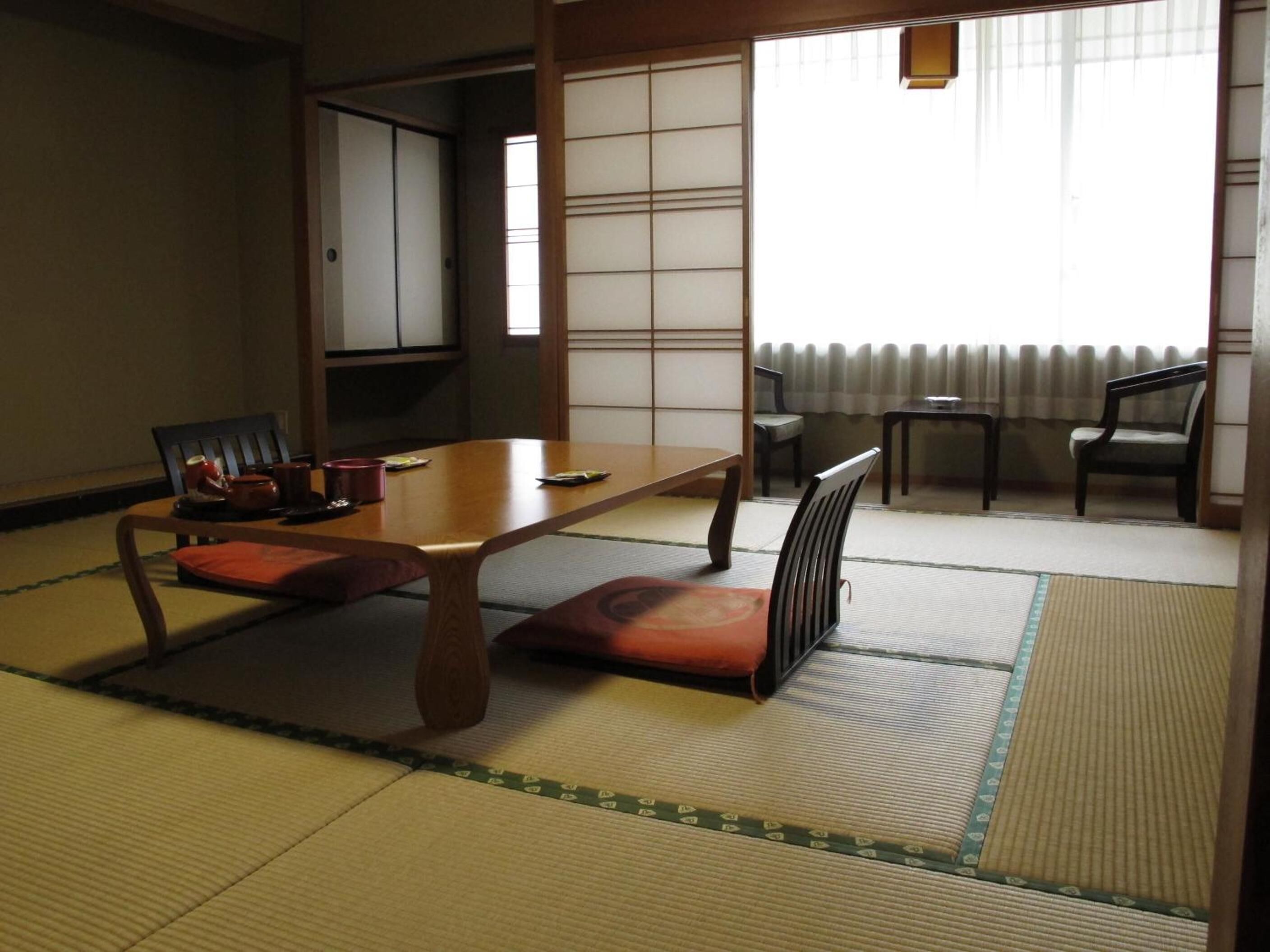 A traditional Japanese room with tatami flooring, a low table, and seating.