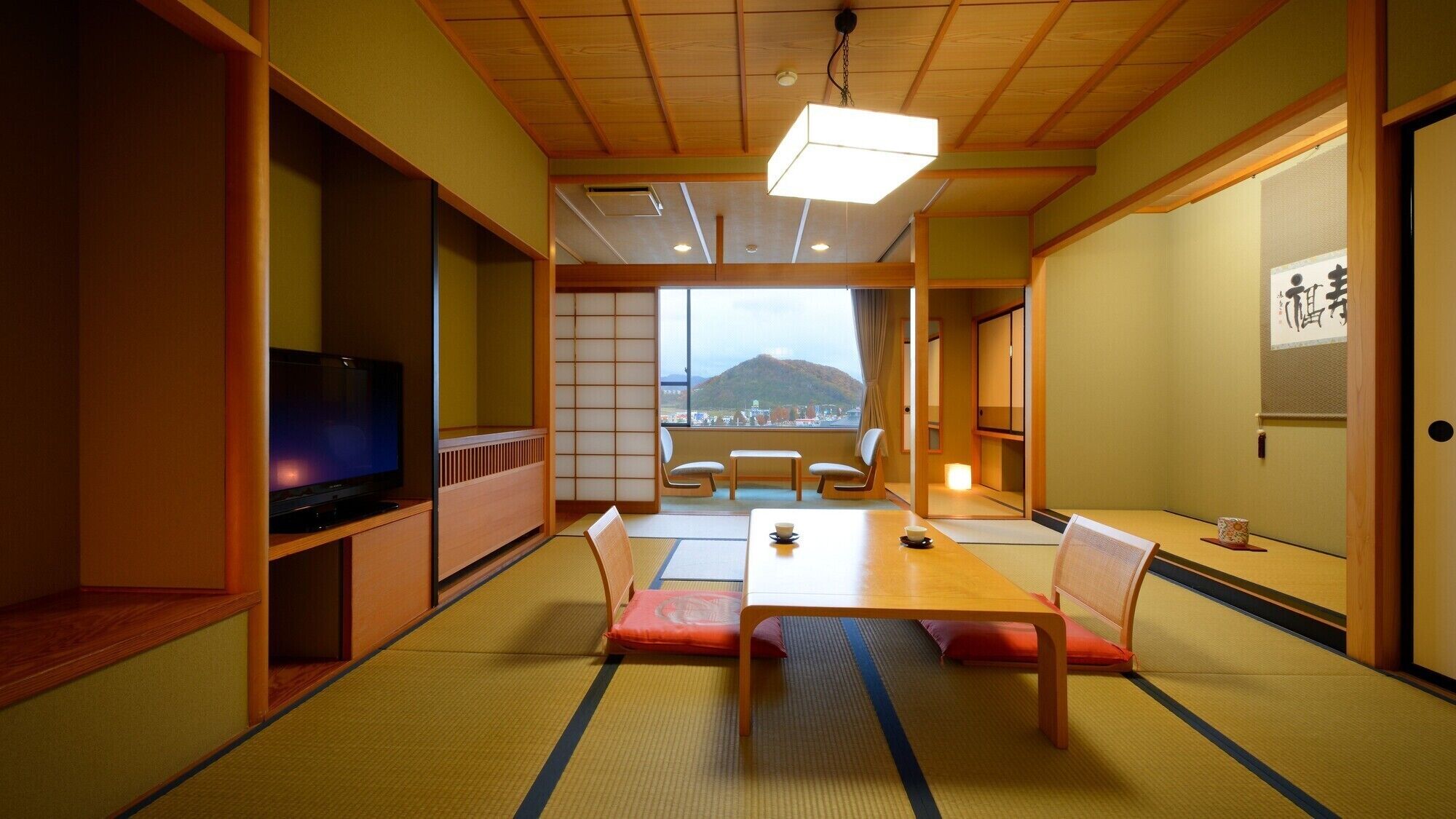 A traditional Japanese room with tatami flooring, a low table, and a television.