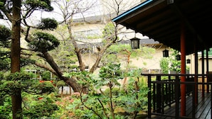 A traditional Japanese garden with a wooden deck and a building in the background. - Sakaeya Hotel (Tendo)