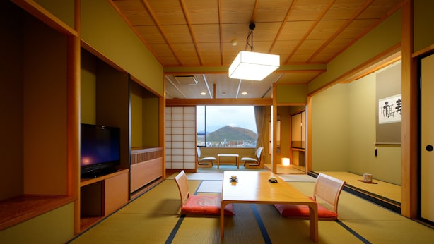 A traditional Japanese room with tatami flooring, a low table, and a television. - Sakaeya Hotel (Tendo)