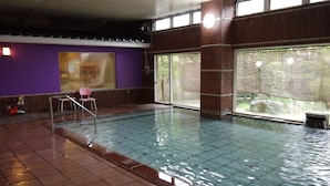 An indoor swimming pool with clear water, a tiled floor, and a purple wall. - Sakaeya Hotel (Tendo)