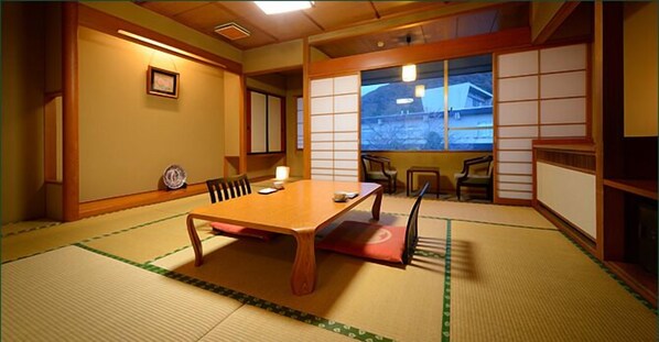 A traditional Japanese room with tatami flooring, a wooden table, and low tables with cushions. - Sakaeya Hotel (Tendo)